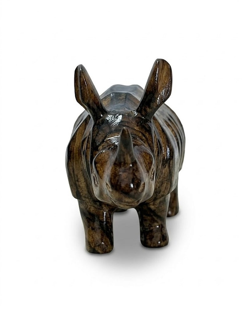 The rhinoceros from the front on a white ground: the horn, the ears, and the polished dark grain over the face.