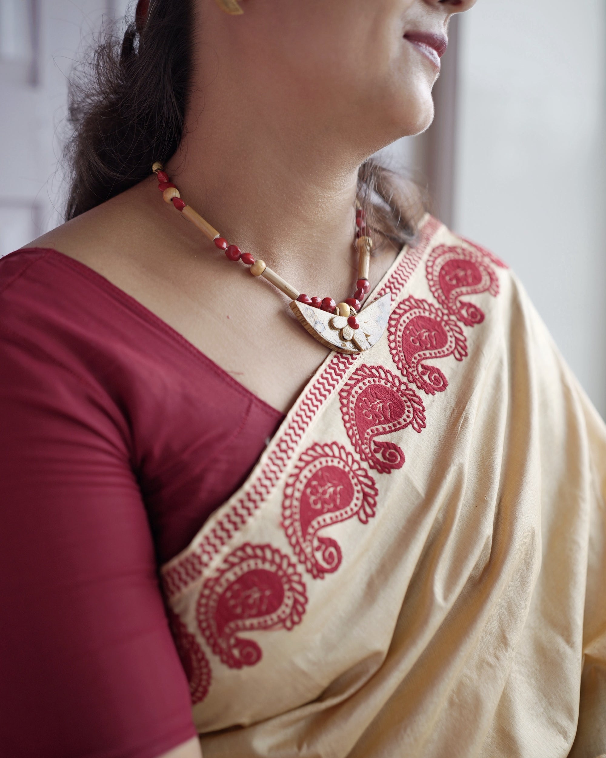 The border across the collarbone, worn with a red and cream bead necklace. Large red paisleys outlined in fine detail against the cream ground.