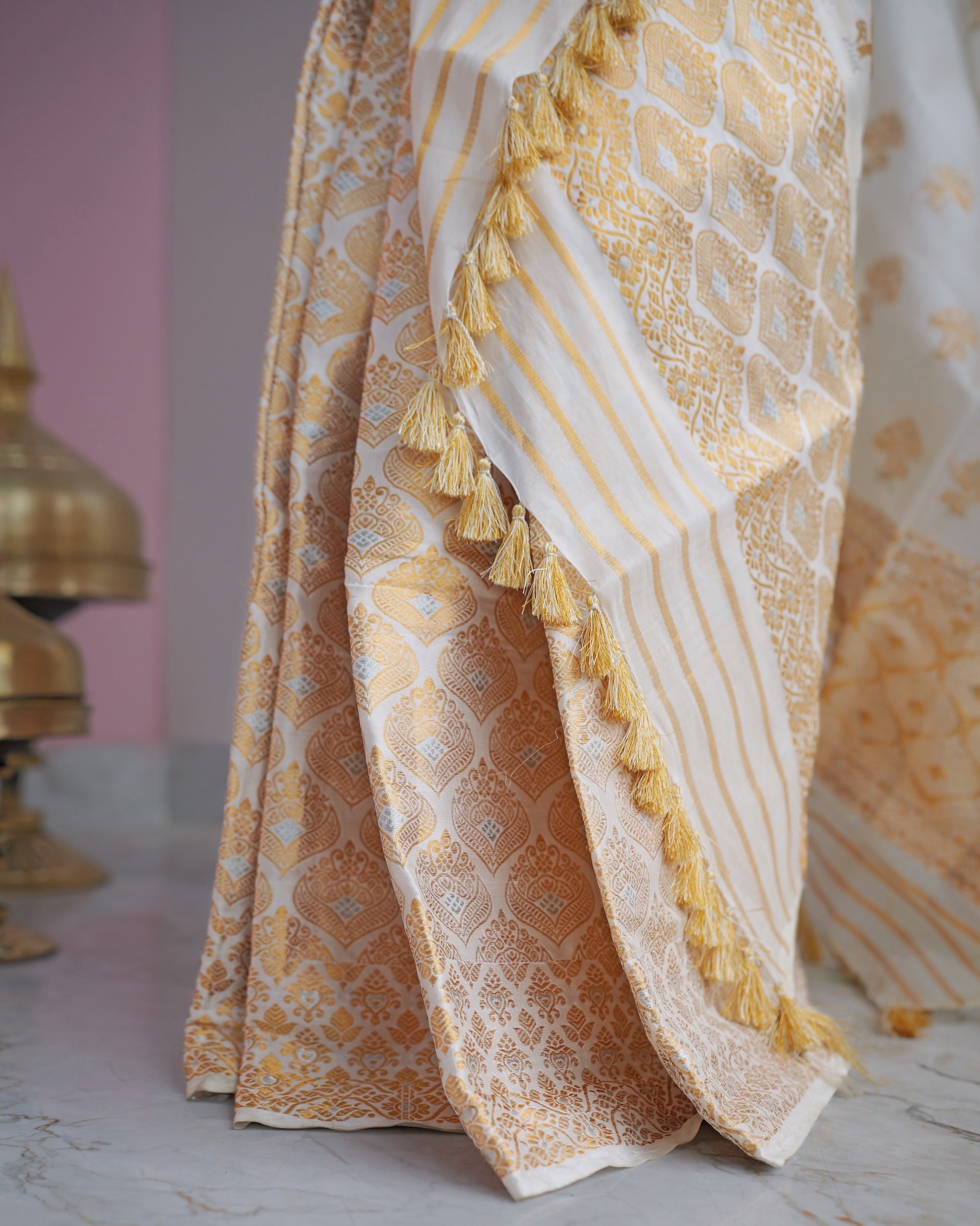 The sador end and the mekhela hem together, gold lattice panels and striped bands finishing in a row of gold tassels.