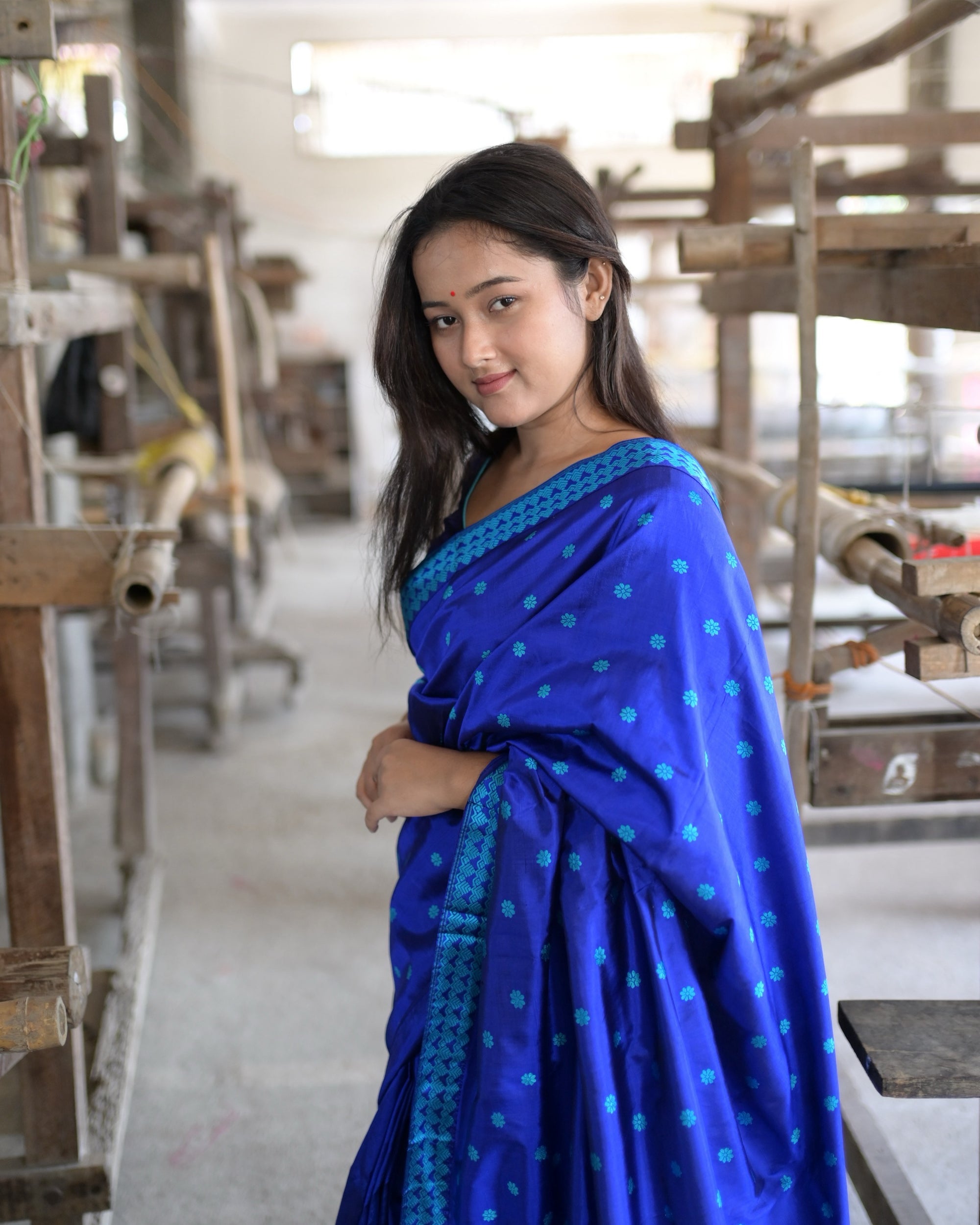 Close, smiling, the pallu wrapped over the shoulder: small turquoise flowers on royal blue and the turquoise chevron border along the edge.