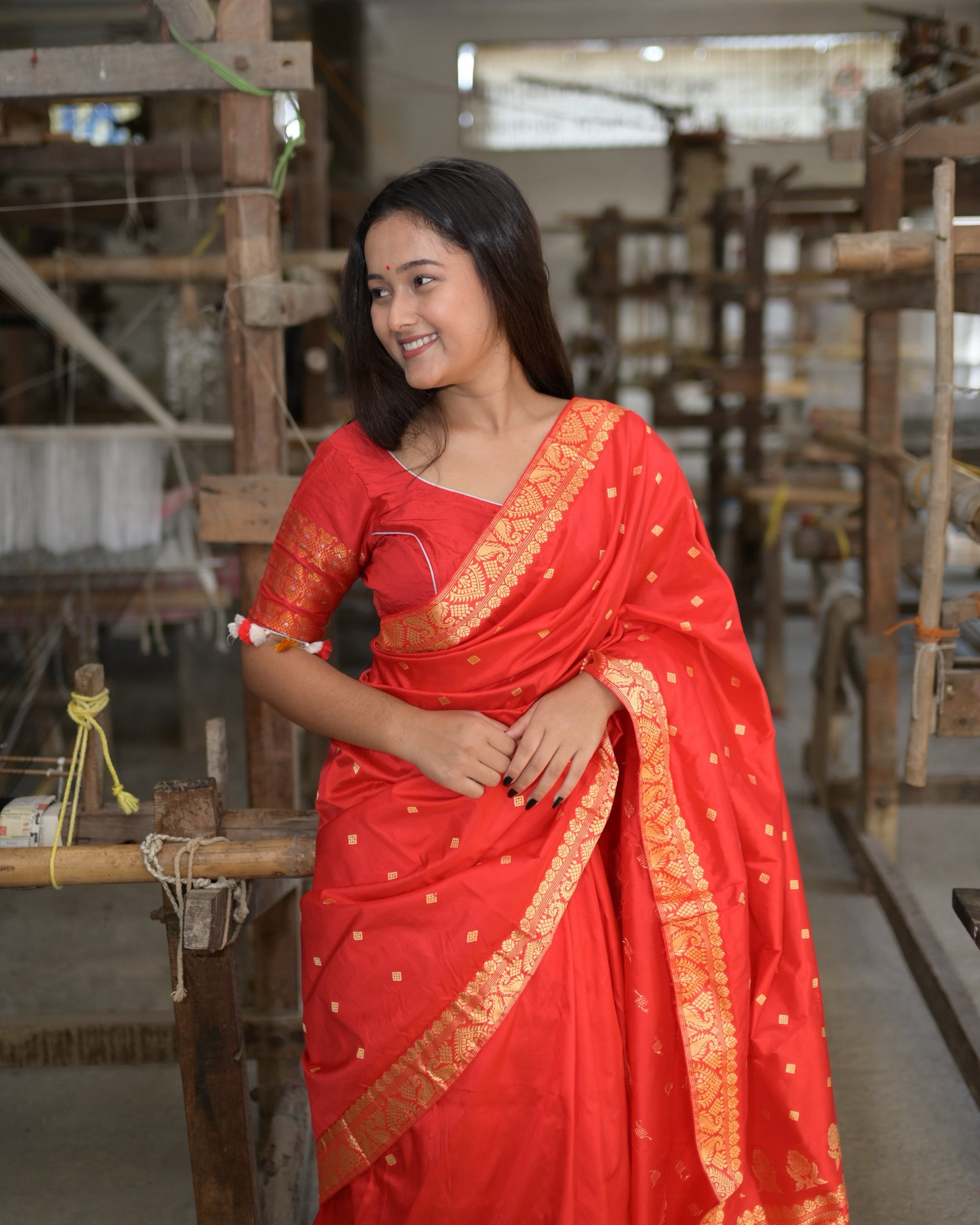 Close, smiling to one side, the pallu over the shoulder: golden squares on red and the broad golden border running down the front.