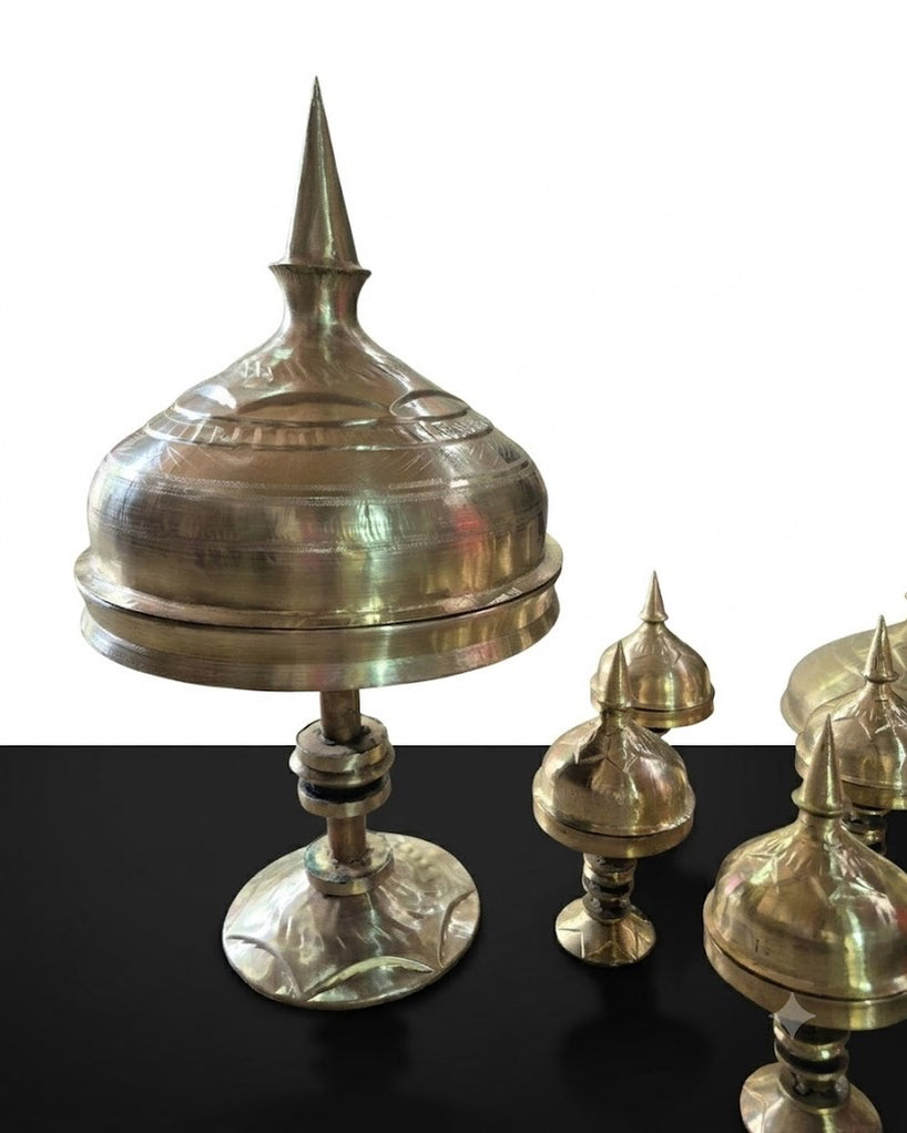 The xorai with its lid on, standing on a black surface against a white wall, with smaller spired lids beside it.