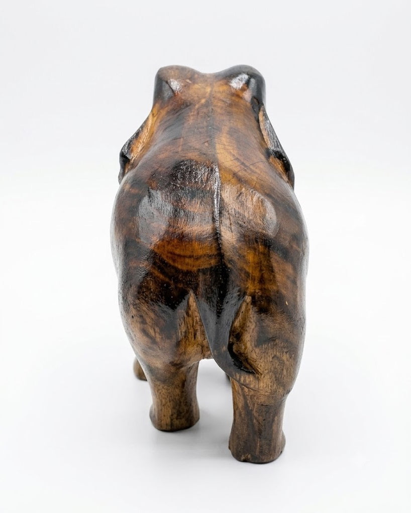 The elephant from behind on a pale ground, the grain running in dark and amber bands down the back and haunches.
