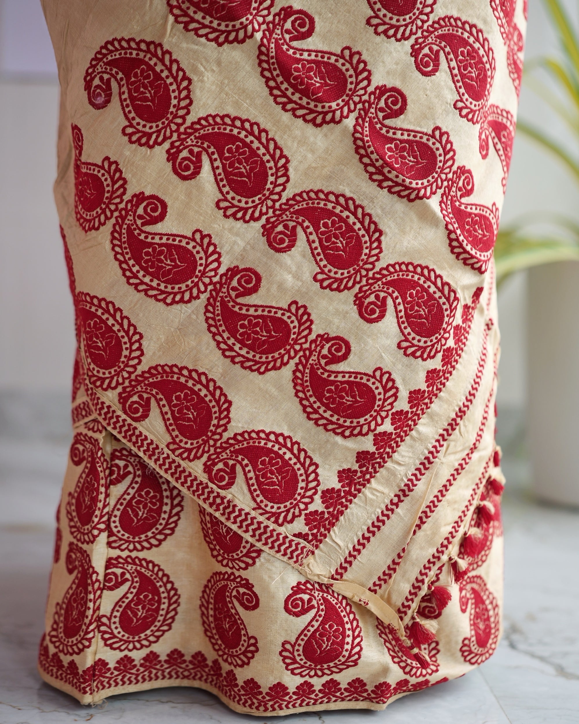 The lower mekhela close up. Rows of large red paisleys set in alternating directions, above a red scalloped hem.