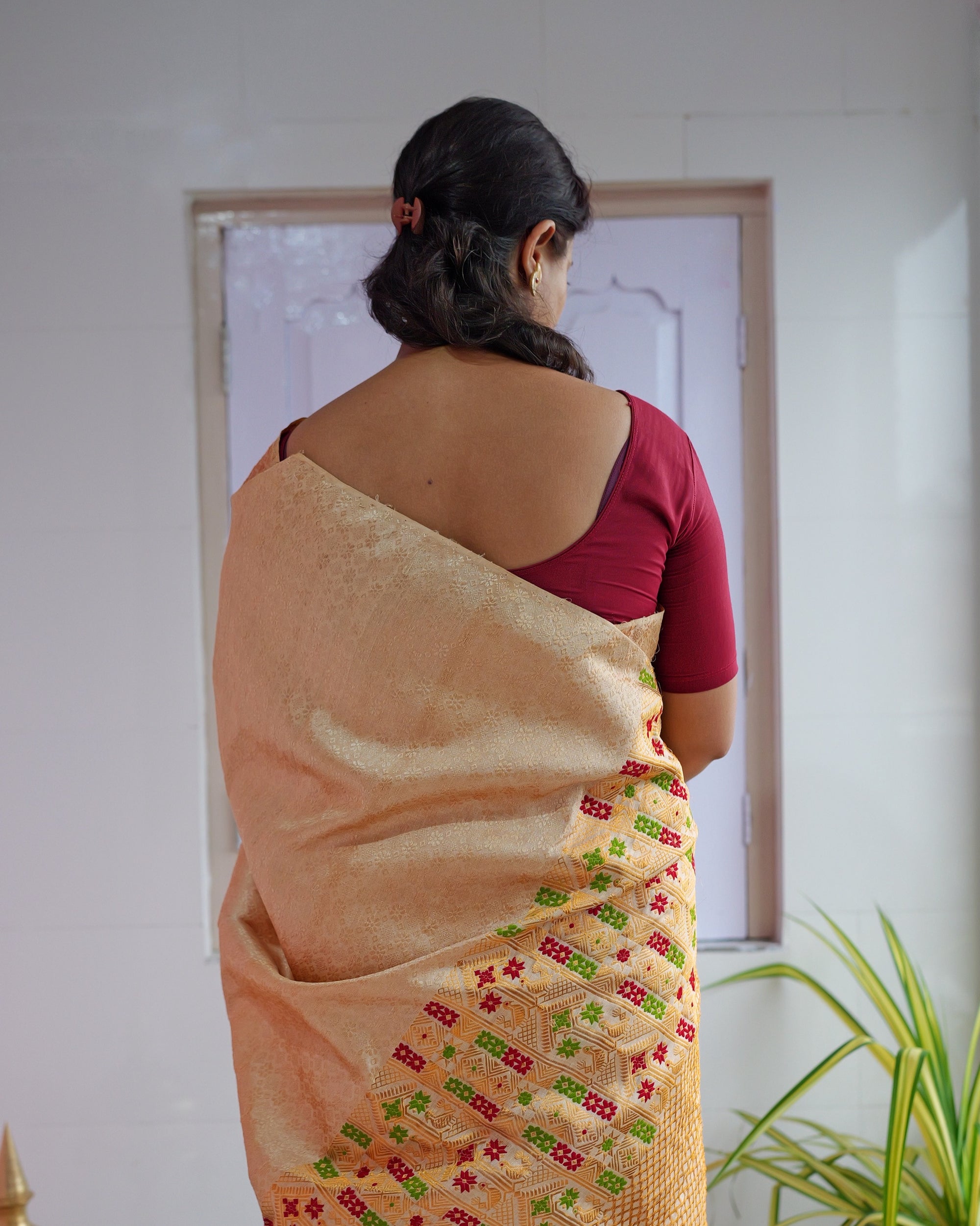 Seen from behind, the drape falling down the back over a maroon blouse, its red and green worked end hanging at the side.