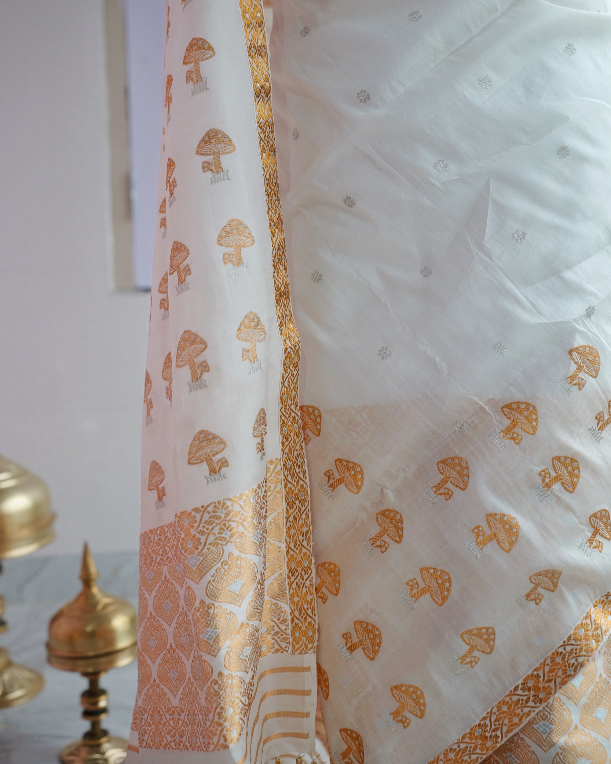 The drape over the mekhela hem. Gold mushroom motifs on ivory, above a wide panel of gold and silver lattice.