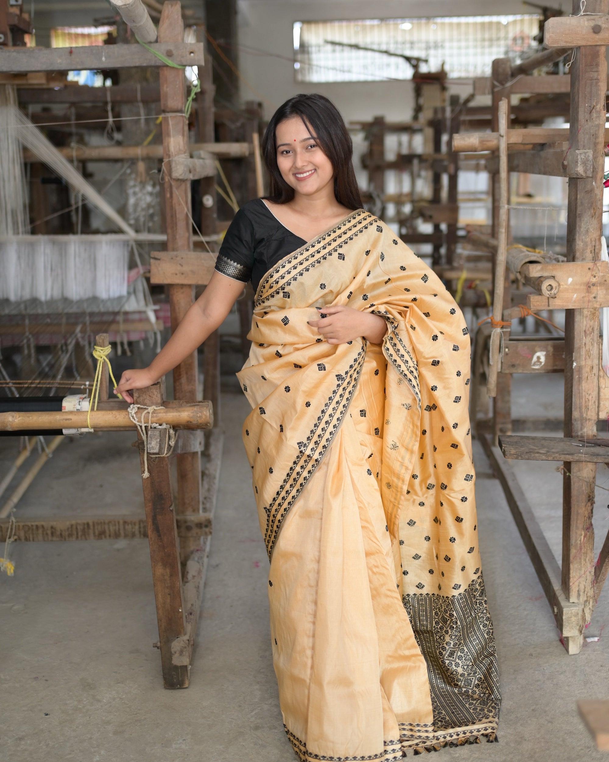 Smiling beside the loom, the pallu gathered at the shoulder: rows of small black flowers and squares, and the black columns of the pallu falling to the floor.