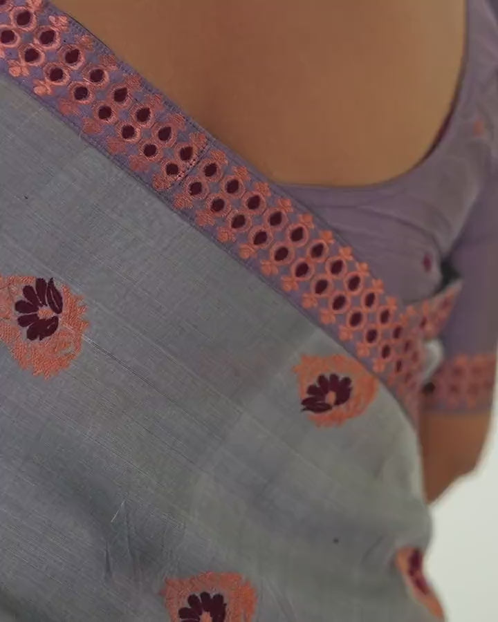 From behind at the shoulder, barely moving: the grey sador with round maroon-and-copper flowers and a copper border dotted with maroon.