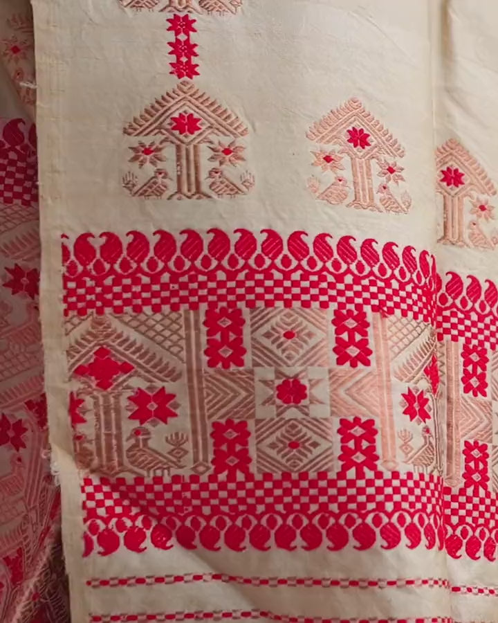 The sador end hanging and swaying slightly: house motifs above a red panel of geometric blocks and fine red stripes.