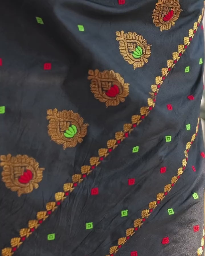 A slow tilt down the black sador: round gold flowers with red and green hearts along a gold border, then gold fan bands near the hem.