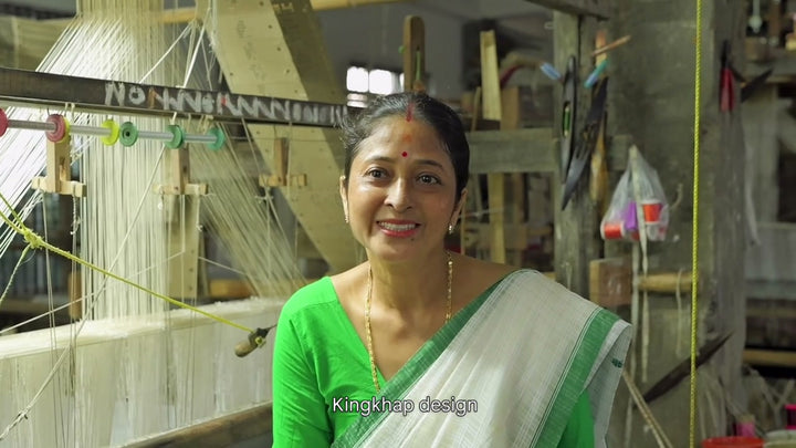 Piju Moni Das at her loom in a green blouse, naming the designs she weaves, Kingkhap, kolsi, mogor and meri, and saying which she loves, with English subtitles. 25 seconds.