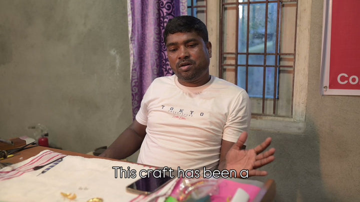 Dibyajyoti Bhuyan at his desk in a cream T-shirt, speaking about Assamese jewellery, which he has made since around 2003 and which came down to him from his great-great-grandfather, with English subtitles. 25 seconds.