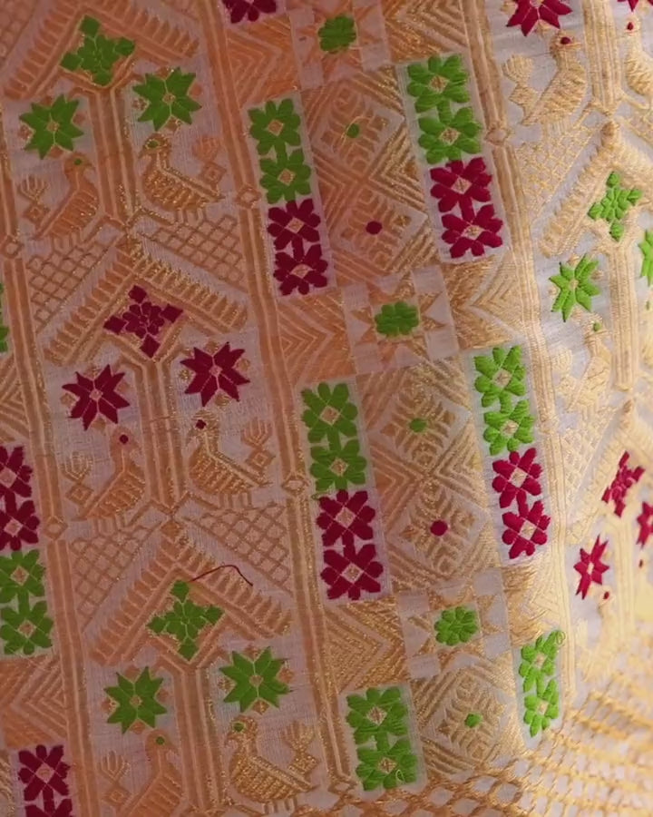 A slow tilt down the hanging sador end: red and green blocks with paired gold birds, a gold diamond grid, then a red band of flowers.