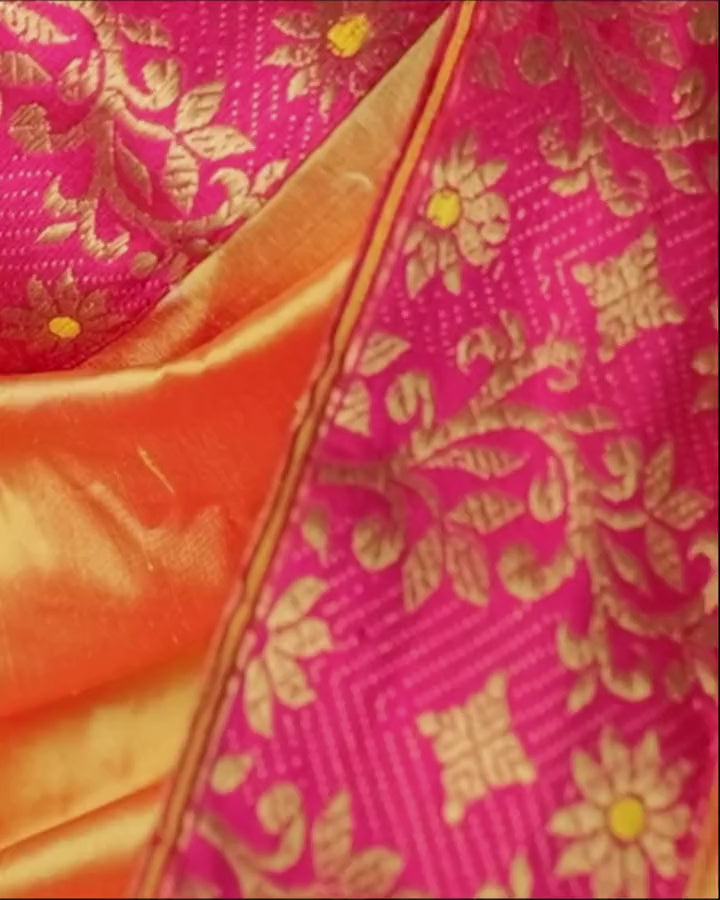 The pink border and pallu fold moving over the marigold body, with gold creepers and pink paisleys.